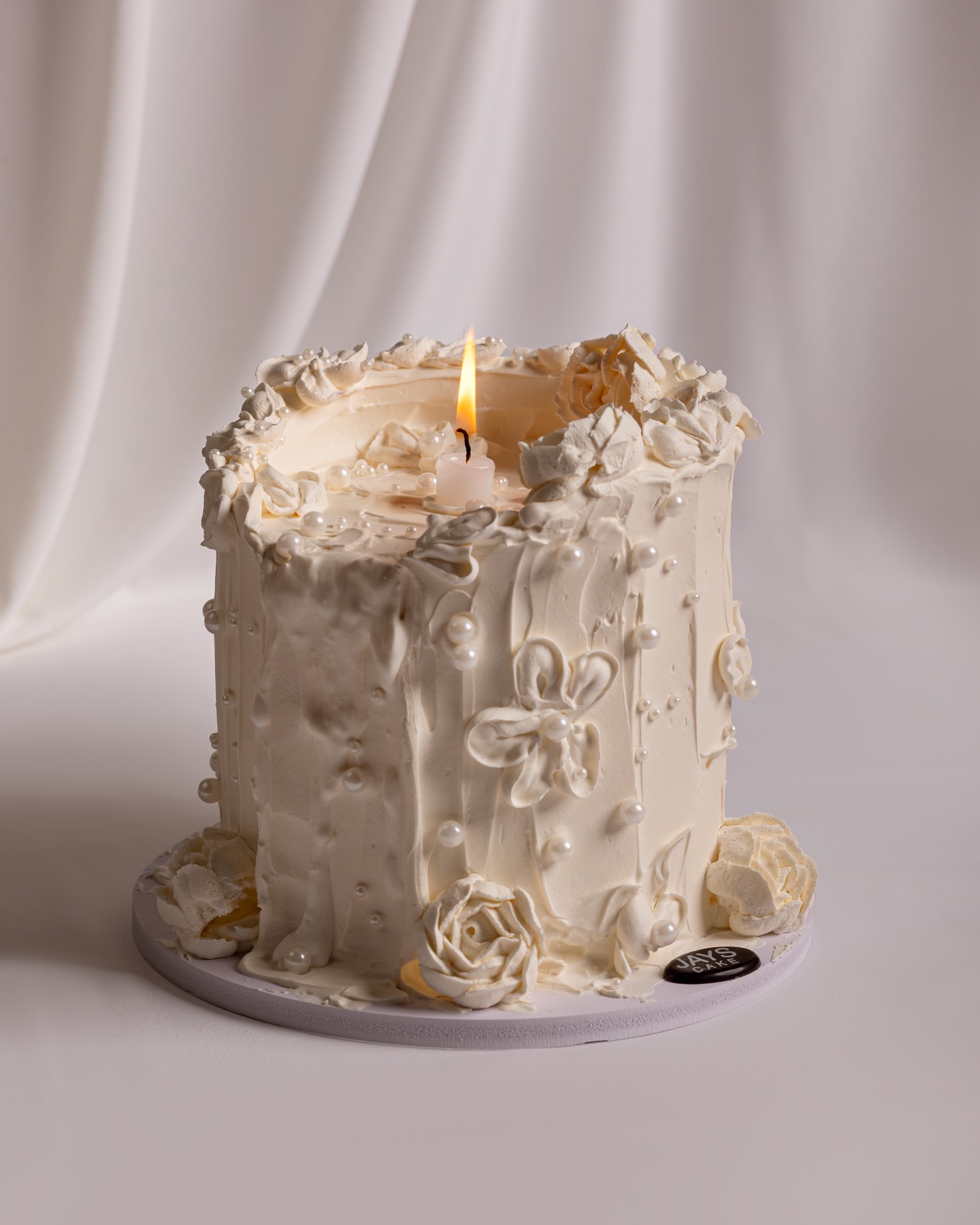 Jays Cakes Facebook ad: Hand-piped florals, soft pearls, and a warm candle…